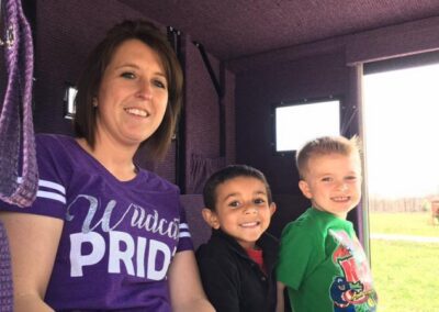a woman and two children sitting in a purple truck